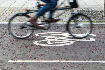 Painted cycle path bicycle sign on the ground with a rider passing.  Motion blurr on the bike and...