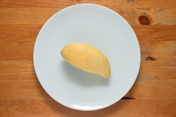 Mango yellow on dish white wood background.