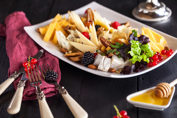 slicing different cheeses in a plate with a glass of wine on the table