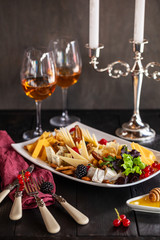 slicing different cheeses in a plate with a glass of wine on the table