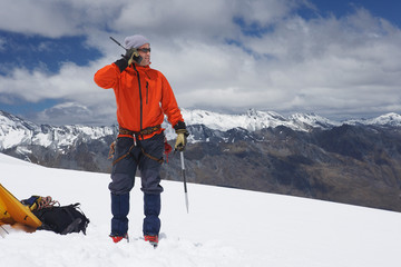 Hiker using walkie-talkie on snowy mountain peak - obrazy, fototapety, plakaty