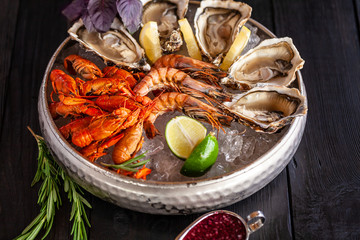 A large plate with seafood on ice. Crayfish, Shrimp and Oysters