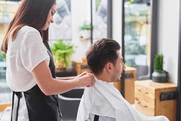 Obraz premium Side view of female hairdresser and man in hair salon