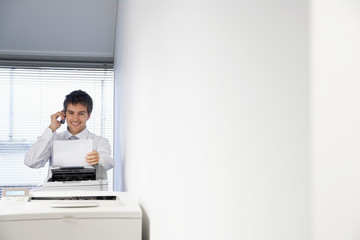 Attractive male business man on the phone and looking a printer paper documents