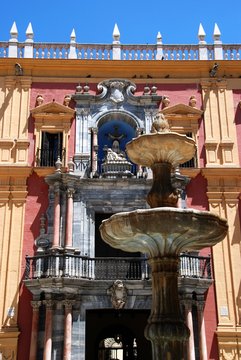 Stone fountain in Obispo Square with the Episcopal Palace to the rear, Malaga, Spain.