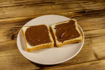Two slices of bread with delicious chocolate hazelnut spread on wooden table
