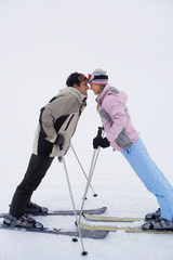 Couple leaning towards each other standing on skis side view