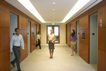People walking in elevator lobby woman standing in middle