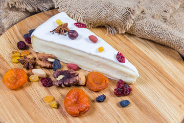 Brie cheese among nuts and dried fruits close-up