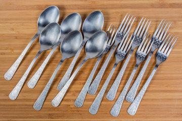 Stainless steel eating utensils on wooden surface, top view