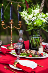 duck breast with grilled asparagus and cherry tomatoes on a table with candles, outdoor at summer