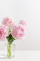 Beautiful pink peony bouquet in glass vase on white background. Spring background, romantic present. Close up. Poster, greeting card, floral background concept