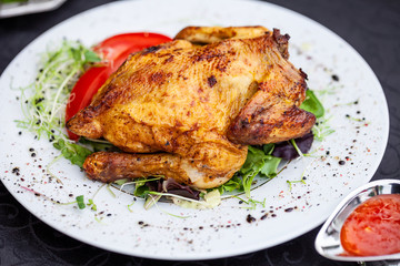 fried full chicken with vegetables and herbs in a plate on the table