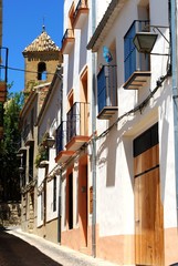 Fototapeta premium Townhouses along a narrow street with a church bell tower to the rear, Ebeda, Spain.