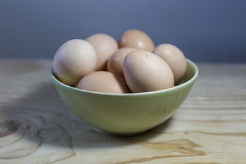 Ceramic bowl with free range eggs on wooden table