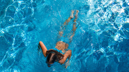 Active girl in swimming pool aerial drone view from above, young woman swims in blue water, tropical vacation, holiday on resort concept