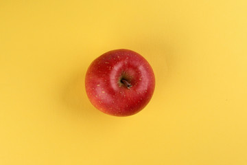 Red apple on yellow colour paper background copy space for text