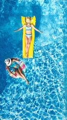 Children in swimming pool aerial drone view fom above, happy kids swim on inflatable ring donut and mattress, active girls have fun in water on family vacation on holiday resort