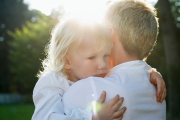 Mother carrying daughter (3-4) in garden