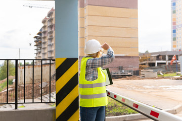 A woman Builder at a construction site inspects a house made of brick