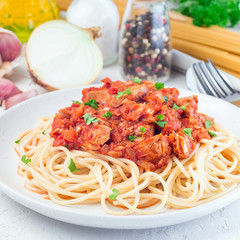 Spaghetti with tuna and tomato basil sauce garnished with parsley, square