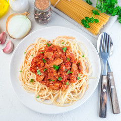 Spaghetti with tuna and tomato basil sauce garnished with parsley, square