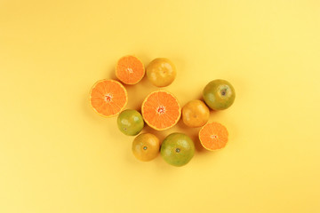 small yellow green mandarin orange whole slice on yellow background copy space for text