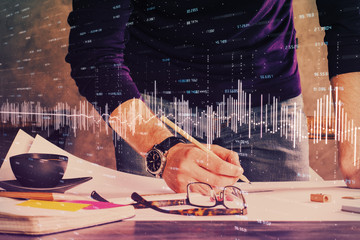 Double exposure of man writing on paper with forex graph.