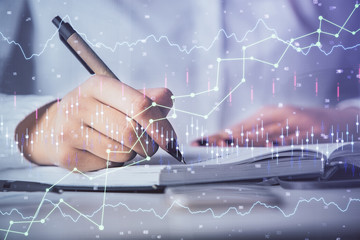 Multi exposure of woman's hands making notes with forex graph hologram. Concept stock market...