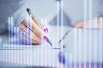 Double exposure of woman's hands making notes with forex graph hologram. Concept stock market analysis.