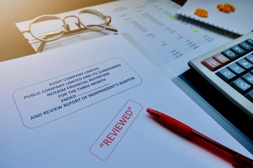 The reviewed financial statement, eyeglass, highlight pencil, calculator, laptop and edited paper....