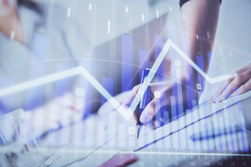 A woman hands writing information about stock market in notepad. Forex chart holograms in front. Concept of research. Double exposure