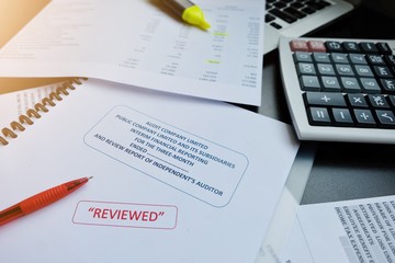 The reviewed financial statement, eyeglass, highlight pencil, calculator, laptop and edited paper....