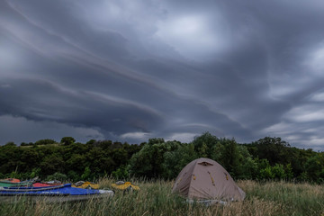 Tourist kayaking camping in the wild. Beautiful cloudy sky on background