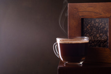 Fresh aromatic coffee in a coffee cup and coffee beans on the table.