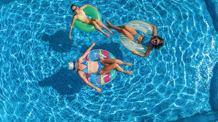 Family in swimming pool aerial drone view from above, happy mother and kids swim on inflatable ring...
