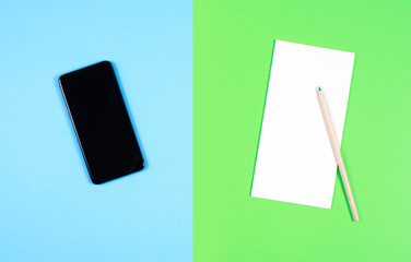 A modern smartphone and a paper notebook with a pencil. The concept of digital detox.