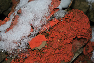 Melting snow on crumbling wall of red bricks, grunge background