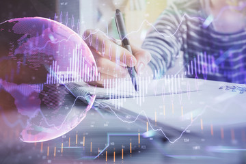 Financial forex graph drawn over hands taking notes background. Concept of research. Double exposure