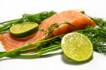 A piece of salted salmon with lemon and herbs closeup. Red fish on a white background