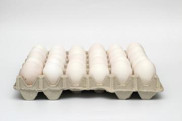 An isolated tray of eggs from recycled materials with 30 white eggs on a white background. Side view