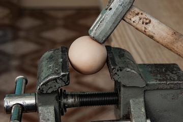 A hammer is about to crush egg shell . Concept of risk, fragile, strength or financial risk.