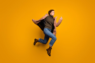 Obraz premium Full length profile photo of funny beautiful lady jump high up rushing shopping center wear casual pink coat pullover jeans leopard footwear isolated yellow color background