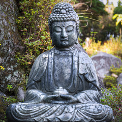 A stone figure of a Buddha sitting with a bowl and meditating.