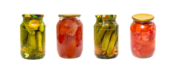 Glass jars with pickles and tomatoes isolated on a white background.
