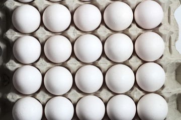 An isolated tray of eggs from recycled materials with white eggs on a white background. Top view