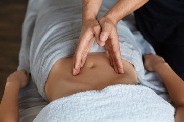 Fototapeta na wymiar Young beautiful woman enjoying anticellulite belly massage in spa.Professional massage therapist is treating a female patient in apartment.Relaxation,beauty,body treatment concept.Home massage.