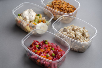 4 lettuce in molds for fast delivery. Pasta with minced meat and onion in navy-style and a jar of vinaigrette on a gray background.