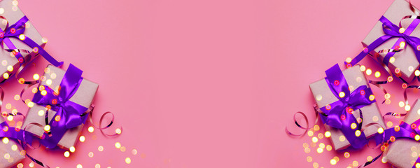 Bright surprise or gift box wrapped in craft paper and silk ribbon bow on a pink background with copy space. Flat lay composition for birthday, mother day or father's day.