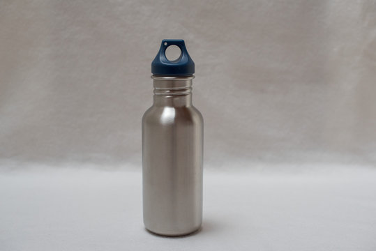 edelstahltrinkflasche mit blauem kunststoff deckel vor wei&szlig;em hintergrund querformat